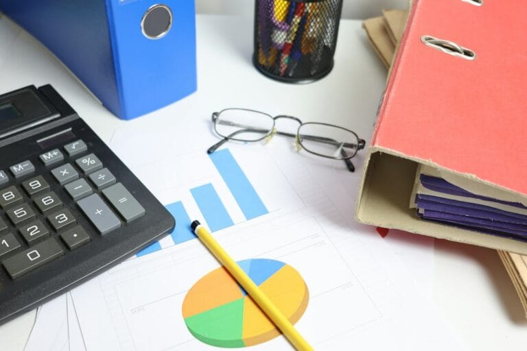 Desk with charts, calculator, and binders representing IT audit salary growth